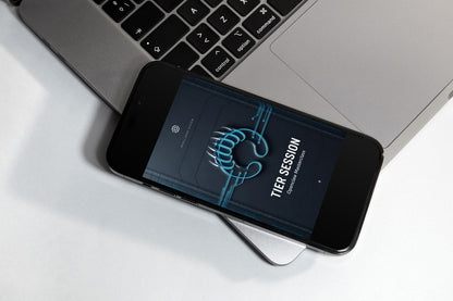 A smartphone on a small display stand showing the 'TIER SESSION' logo on its screen, set against a dark gray textured background.